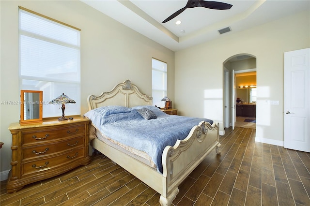 bedroom featuring arched walkways, multiple windows, dark wood-type flooring, and visible vents