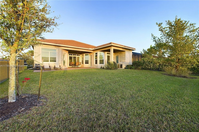 back of house featuring stucco siding, fence, and a yard