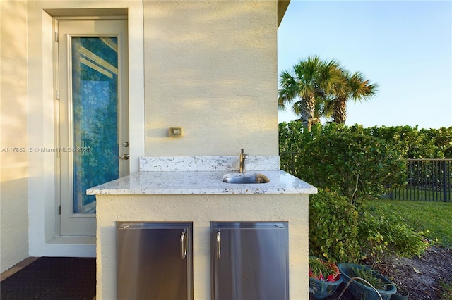 details featuring indoor wet bar, a sink, stucco siding, and fence