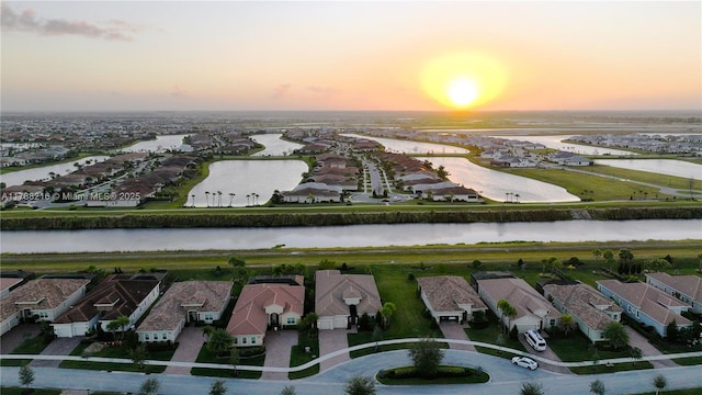 aerial view at dusk featuring a residential view and a water view