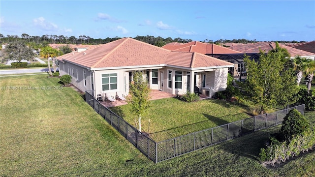 view of front of home featuring a fenced backyard, a tile roof, a front yard, and stucco siding