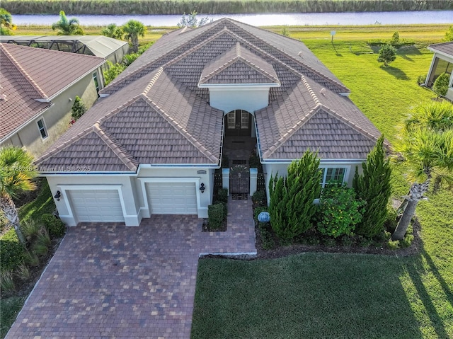 view of front of house with a tile roof, a garage, a front yard, stucco siding, and decorative driveway