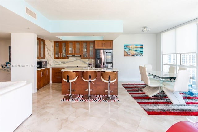 480 NE 30th St Unit 1807, Miami, FL 33137 - kitchen featuring brown cabinetry, visible vents, glass insert cabinets, light countertops, and stainless steel appliances