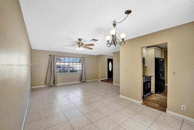 empty room featuring light tile patterned floors, visible vents, ceiling fan with notable chandelier, and baseboards