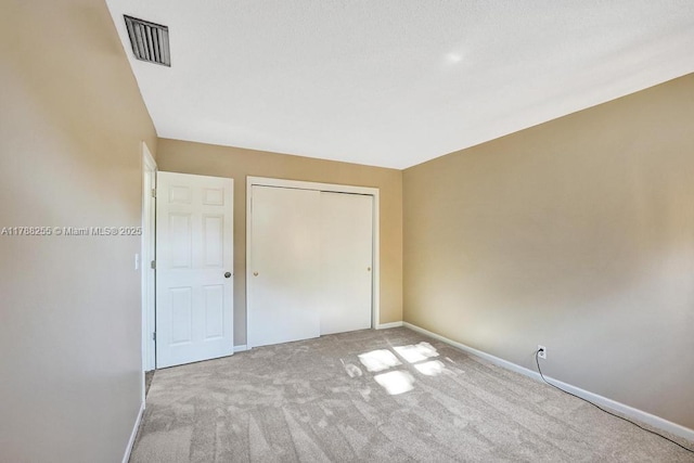 unfurnished bedroom with visible vents, a closet, baseboards, and carpet floors