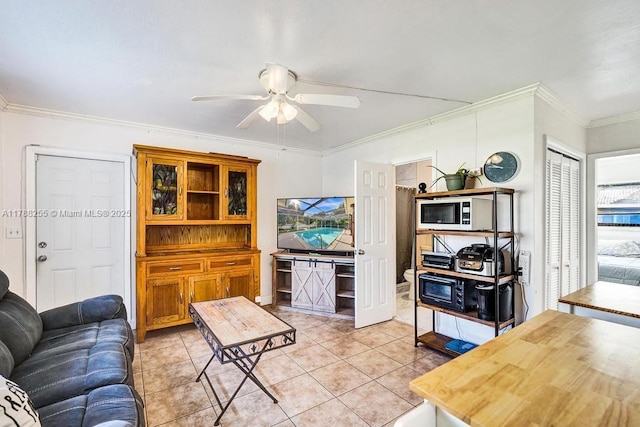 living area featuring light tile patterned floors, ceiling fan, and crown molding