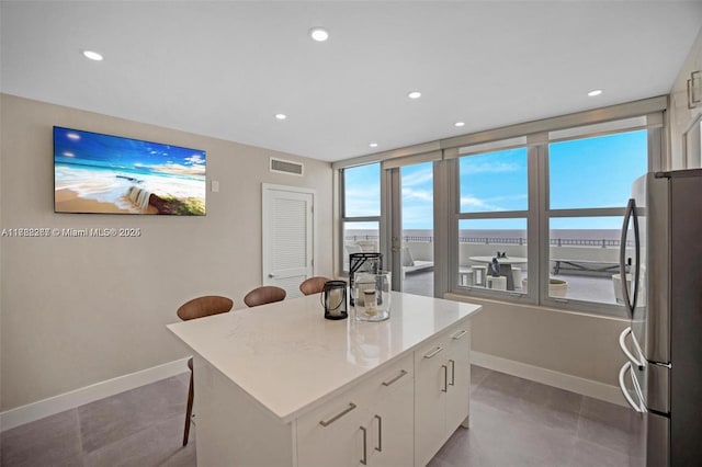 2899 Collins Ave Pha, Pha, Miami Beach, FL 33140 - kitchen with white cabinets, visible vents, baseboards, freestanding refrigerator, and a breakfast bar area