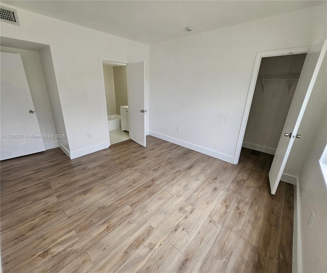 450 NW 84th St Unit 450, Miami, FL 33150 - unfurnished bedroom with light wood-style floors, a closet, baseboards, connected bathroom, and a walk in closet
