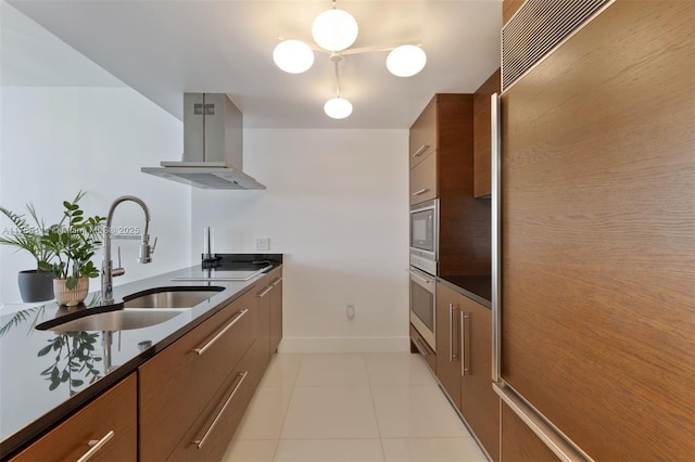 kitchen with wall chimney exhaust hood, a sink, baseboards, built in appliances, and modern cabinets