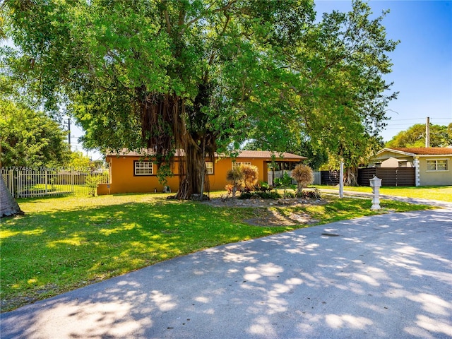 view of front facade with stucco siding, a front yard, and fence