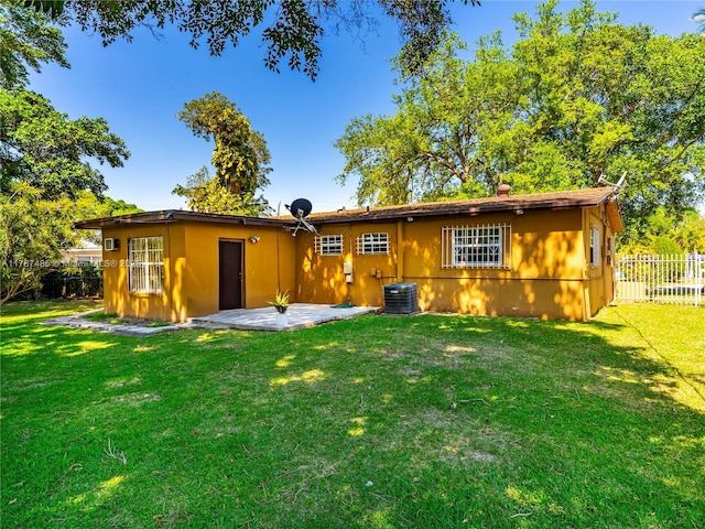 rear view of house with a yard, central AC, and fence
