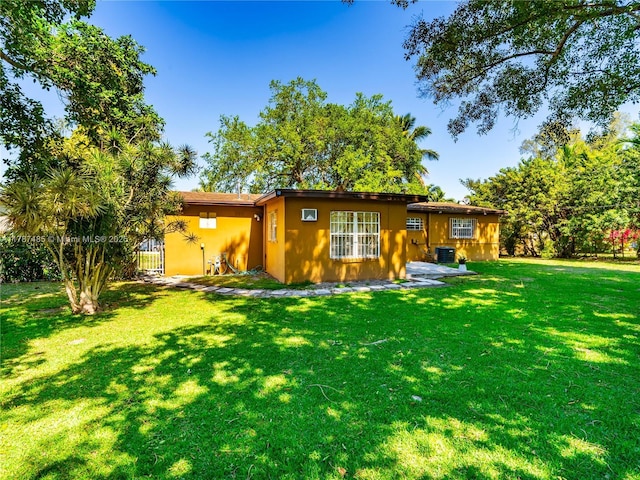 back of property with central air condition unit and a lawn
