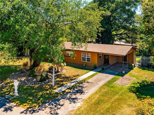 single story home featuring a front lawn, driveway, fence, an attached carport, and stucco siding