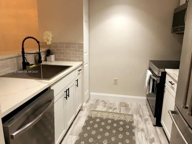 511 Lucerne Ave Unit 408, Lake Worth, FL 33460 - kitchen featuring a sink, stainless steel appliances, decorative backsplash, white cabinets, and light stone counters