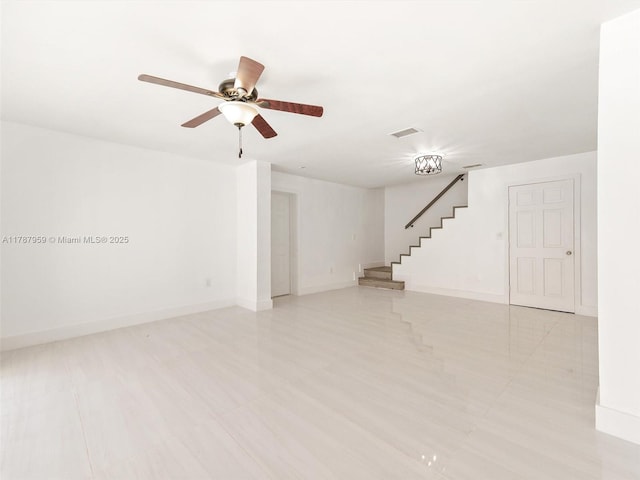 unfurnished living room with stairway, visible vents, baseboards, and ceiling fan