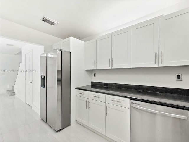 kitchen with white cabinets, dark countertops, stainless steel appliances, and visible vents