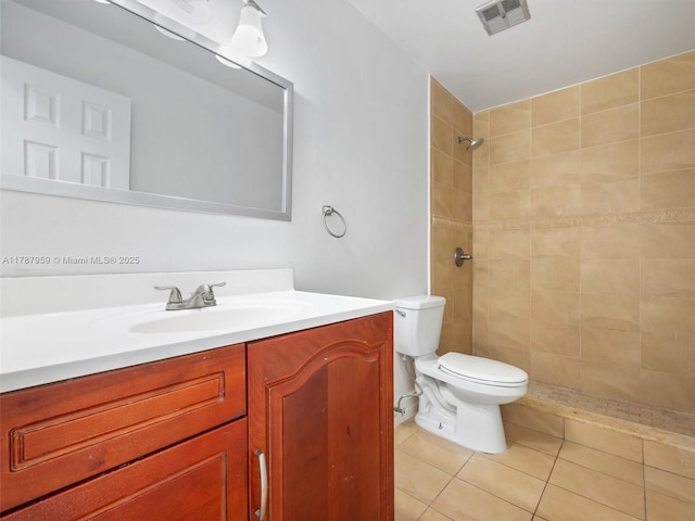 bathroom featuring tile patterned floors, toilet, tiled shower, visible vents, and vanity