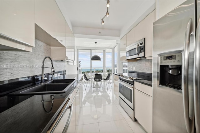 kitchen featuring dark countertops, white cabinets, light tile patterned floors, backsplash, and appliances with stainless steel finishes