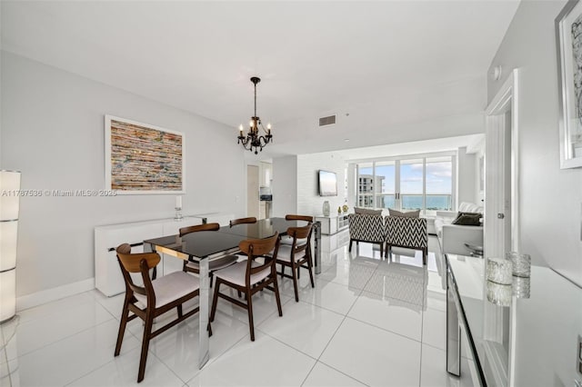 dining area featuring a chandelier, visible vents, light tile patterned flooring, and a water view