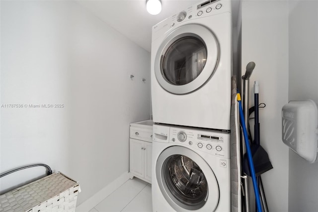 21055 Yacht Club Dr Unit 3101, Aventura, FL 33180 - clothes washing area featuring light tile patterned flooring, cabinet space, stacked washer and clothes dryer, and baseboards