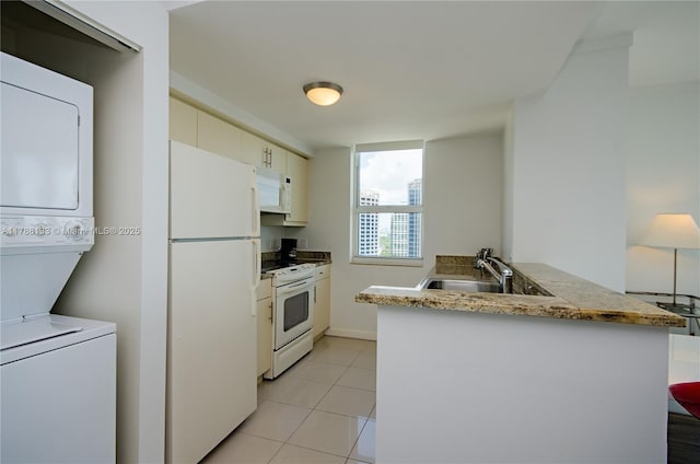 2889 Mcfarlane Rd Unit 1601, Coconut Grove, FL 33133 - kitchen with white appliances, light tile patterned floors, a sink, stacked washing maching and dryer, and a peninsula