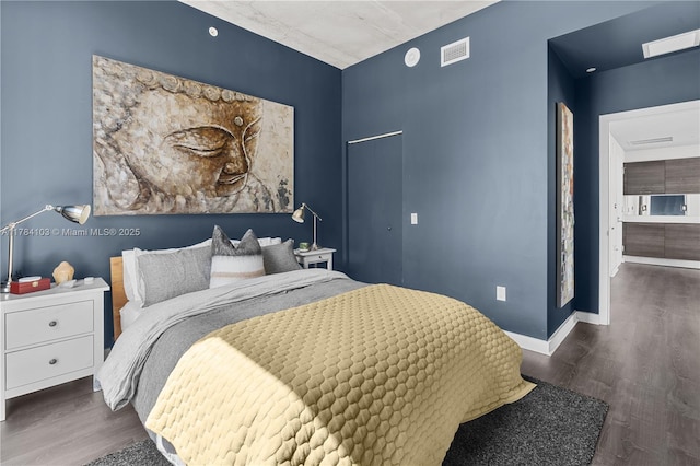 bedroom featuring baseboards, visible vents, and wood finished floors