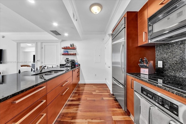 kitchen with brown cabinetry, backsplash, light wood-style floors, and black appliances