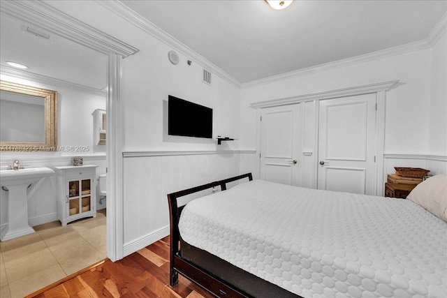bedroom with visible vents, a wainscoted wall, and ornamental molding