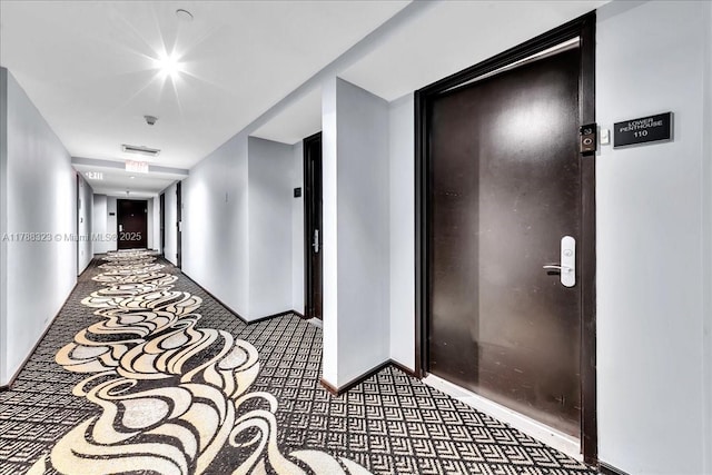 hallway with carpet floors, elevator, and baseboards