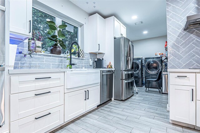 kitchen with washer and dryer, backsplash, light countertops, and stainless steel appliances