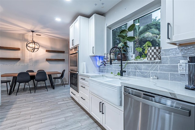 kitchen featuring white cabinetry, stainless steel appliances, light stone counters, and a sink