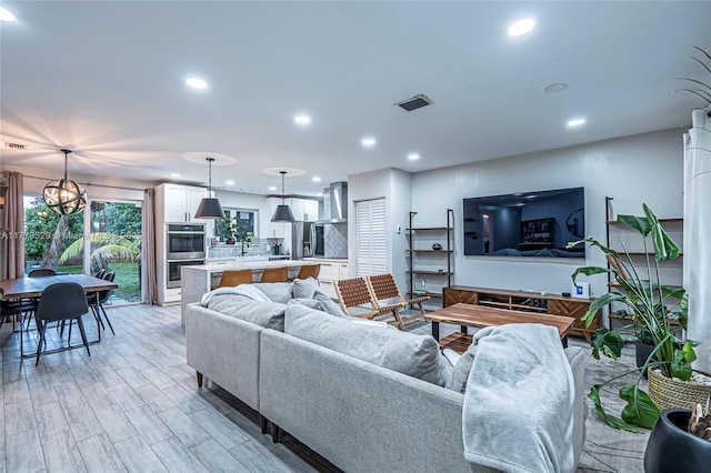 living room featuring a chandelier, visible vents, recessed lighting, and light wood-style flooring