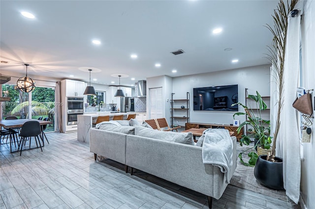 living area with a notable chandelier, recessed lighting, light wood finished floors, and visible vents