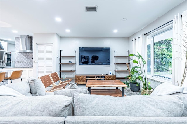 living room with recessed lighting, visible vents, and wood finished floors