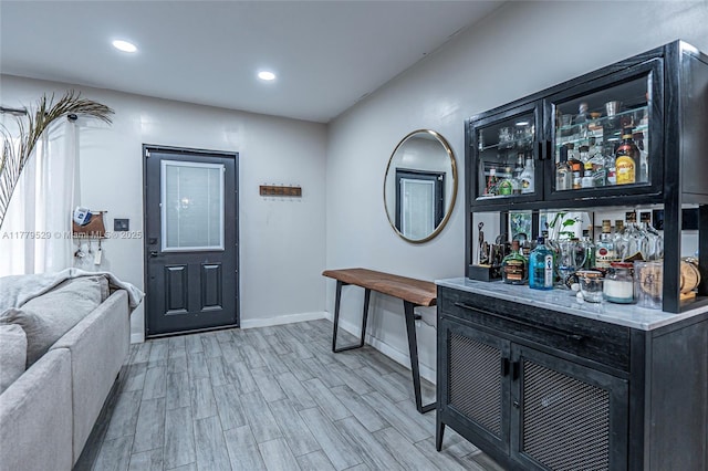 foyer entrance with a dry bar, wood finished floors, recessed lighting, and baseboards