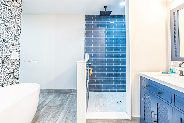 bathroom with a tile shower, a freestanding bath, wood finished floors, and vanity