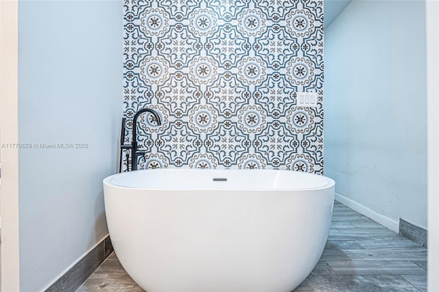 bathroom with a freestanding tub, wood finished floors, and baseboards