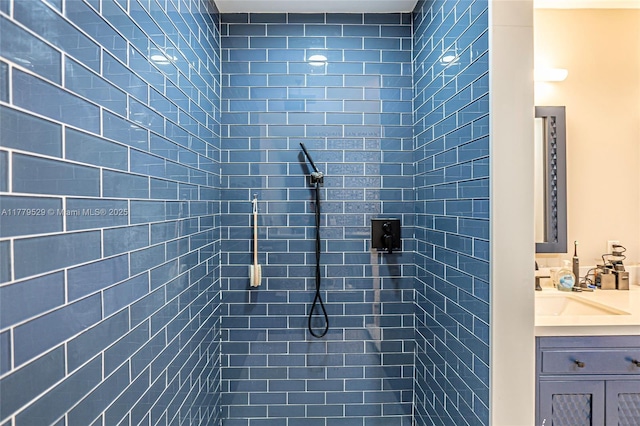 bathroom with tiled shower and vanity