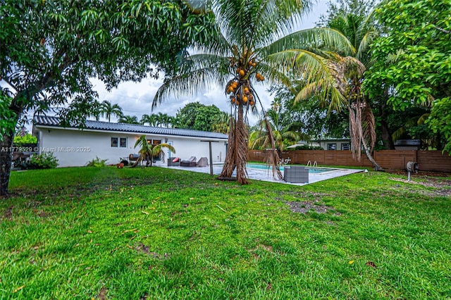 rear view of property featuring a patio area, a yard, a fenced backyard, an outdoor pool, and stucco siding