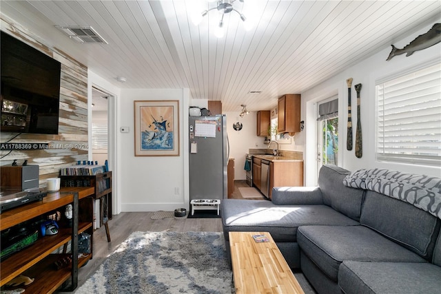 living area featuring light wood finished floors, baseboards, visible vents, a ceiling fan, and wood ceiling