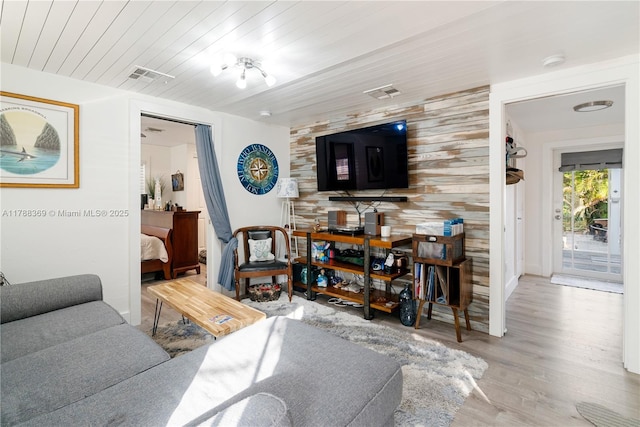 living room featuring visible vents, wooden walls, wood finished floors, and wood ceiling