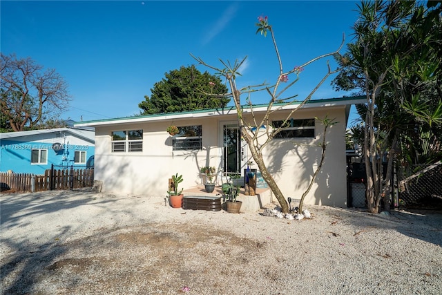 view of front of house featuring stucco siding and fence