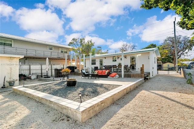 back of house with fence, an outdoor living space with a fire pit, a patio, metal roof, and a standing seam roof