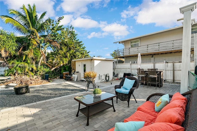 view of patio featuring outdoor lounge area, an outbuilding, a storage unit, and fence