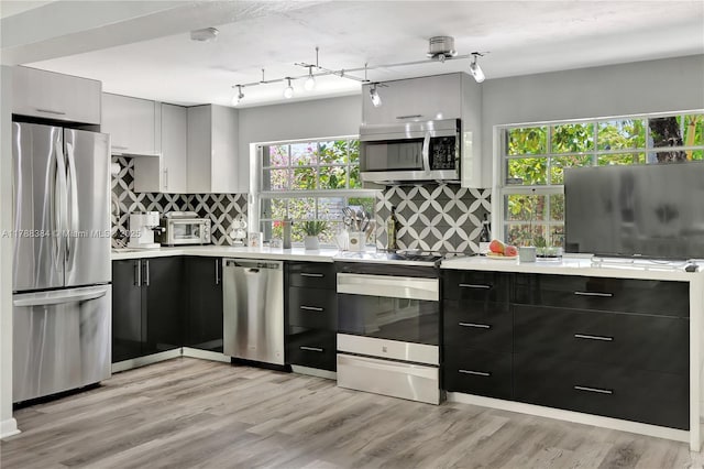 3375 SW 29th Ter, Miami, FL 33133 - kitchen featuring appliances with stainless steel finishes, light countertops, decorative backsplash, and light wood finished floors