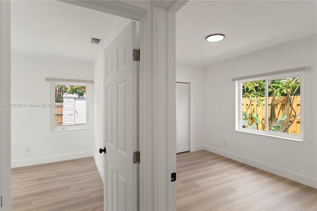 unfurnished bedroom featuring baseboards, light wood-style floors, and visible vents