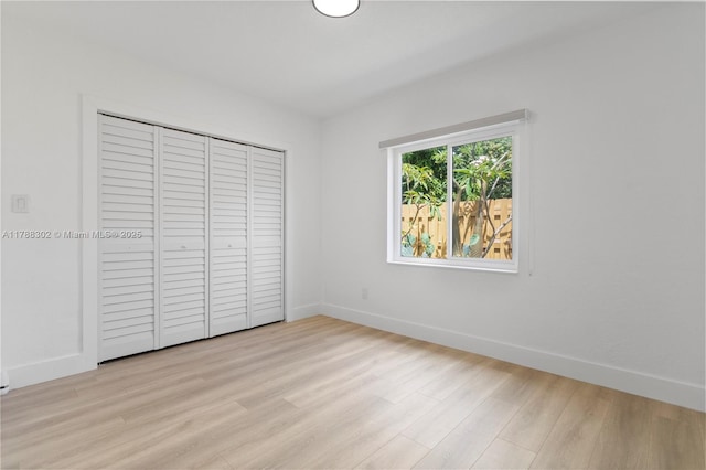 unfurnished bedroom with a closet, light wood finished floors, and baseboards