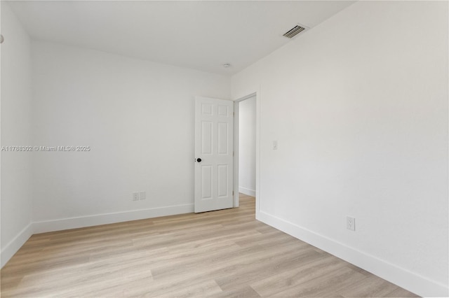 spare room featuring baseboards, visible vents, and light wood finished floors