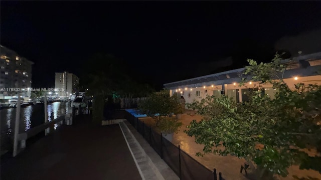 patio at twilight featuring a water view and a dock