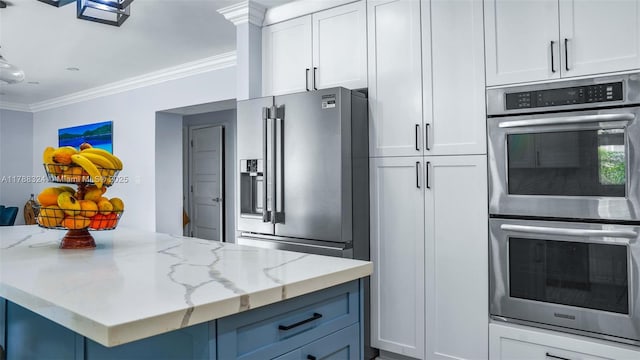 2105 Arch Creek Dr, North Miami, FL 33181 - kitchen with stainless steel appliances, ornamental molding, light stone countertops, white cabinetry, and a center island